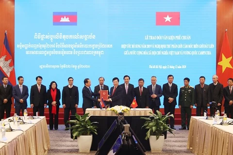 Заместитель премьер-министра и министр иностранных дел Фам Бинь Минь (спереди справа) передает ратификационный документ послу Камбоджи Чай Навуту в Ханое 22 декабря (Фото: ВИА)