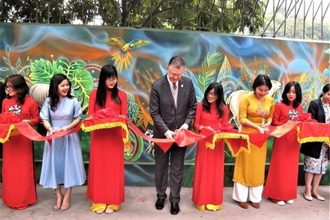 Посол США во Вьетнаме Дэниел Дж. Критенбринк перерезает ленту, чтобы открыть настенную роспись на внешней стене Американского клуба в Ханое 15 января. (Фото: ВИА)