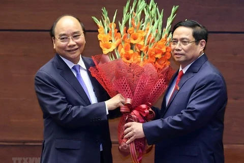 Премьер-министр Фам Минь Тьинь (справа) вручает цветы президенту страны Нгуен Суан Фуку, который был премьер-министром Вьетнама в 2016-2021 годах. (Фото: ВИА)