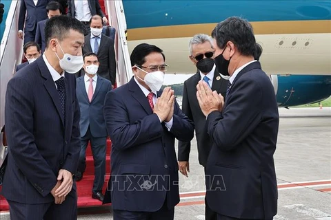 Официальные лица и сотрудники посольства Вьетнама в Индонезии и Постоянного представительства Вьетнама в АСЕАН приветствуют премьер-министра Фам Минь Тьиня в международном аэропорту Сукарно-Хатта. (Фото: ВИА)