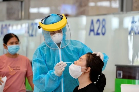 У пассажира, готовящегося к вылету из Ханоя в город HCM, берется проба для тестирования на COVID-19 (Фото: ВИА)