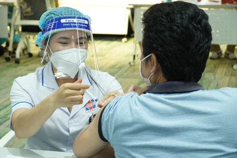 Медицинский работник делает прививку от COVID-19 мужчине в Хошимине. (Фото: ВНА)