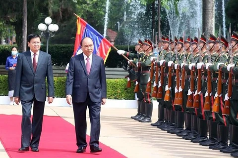 Генеральный секретарь, президент Лаоса Тонглун Сисулит и президент Нгуен Суан Фук осматривают почетный караул. (Фото: ВИА)