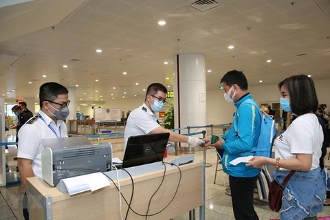 Медицинский персонал проверяет медицинскую декларацию пассажира до прохождения иммиграционных процедур в международном аэропорту Нойбай. (Фото: ВИА)