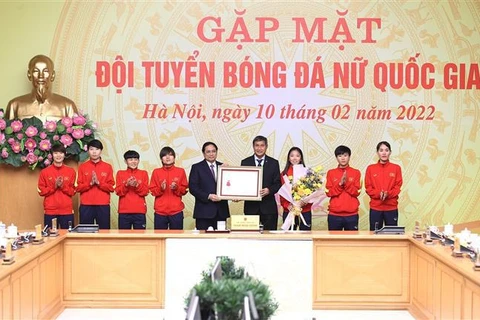 Тренер Май Дык Чунг от имени женской сборной Вьетнама по футболу вручает сувениры премьер-министру Фам Минь Тьиню. (Фото: ВИА)