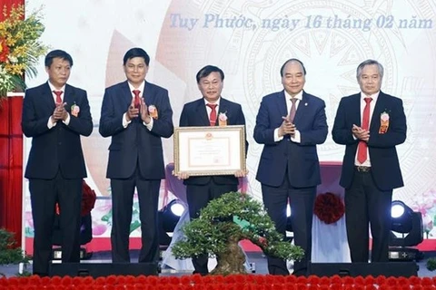 Президент Нгуен Суан Фук (второй справа) вручает свидетельство о признании уезда Туйфыок в южно-центральной провинции Биньдинь отвечающим критериям новой деревни. (Фото: ВИА)