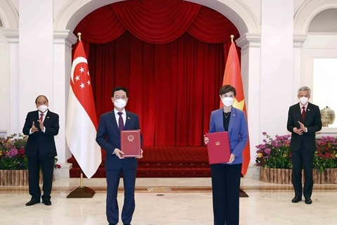 Президент Вьетнама Нгуен Суан Фук (первый слева) и премьер-министр Сингапура Ли Сяньлун (первый справа) наблюдают за обменом документами о сотрудничестве между двумя странами 25 февраля. (Фото: ВИА)