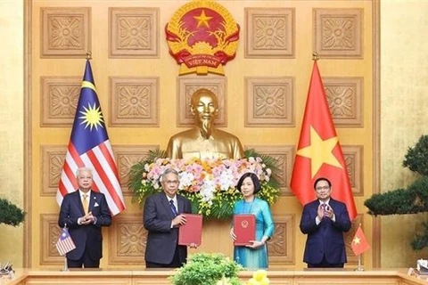 Премьер-министр Фам Минь Тьинь (справа) и его коллега из Малайзии Дато Шри Исмаил Сабри бин Яакоб (слева) наблюдают за обменом соглашением о сотрудничестве между ВИА и BERNAMA (Фото: ВИА)