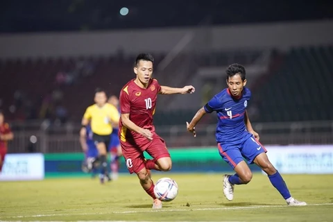 Нгуен Ван Куйет из Вьетнама (в красной форме) и сингапурский игрок соревнуются за мяч в игре вечером 21 сентября. (Фото: ВИА) 