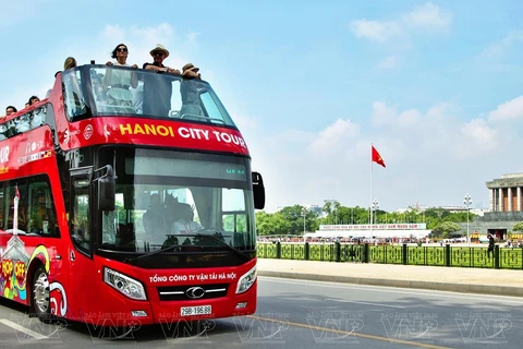 Иностранные туристы наслаждаются пейзажем Мавзолея Хо Ши Мина и площади Бабинь на двухэтажном автобусе. (Фото: ВИА) 
