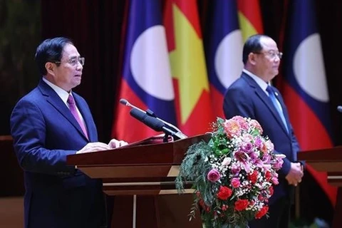 Премьер-министр Фам Минь Тьинь (слева) и его лаосский коллега Сонексай Сифандоне на церемонии завершения Года солидарности и дружбы Вьетнам-Лаос, Лаос-Вьетнам 2022, 11 января. (Фото: ВИА) 