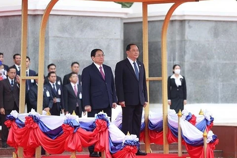 Премьер-министр Фам Минь Тьинь и премьер-министр Лаоса Сонексай Сипандоне слушают национальные гимны двух стран. (Фото: ВИА)