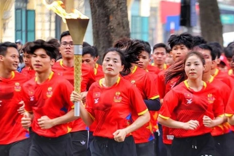 Вьетнамская бегунья Нгуен Тхи Хуйен, многократный победитель Игр Юго-Восточной Азии, и выдающиеся вьетнамские спортсмены проносят факел по району озера Хоанкьем. (Фото: ВИА) 