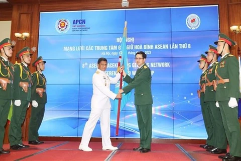 Полковник Фам Мань Тханг, директор Департамента миротворческих операций Вьетнама (справа) передает флаг сети представителю Индонезии в качестве председателя APCN 2024. (Фото: ВИA)