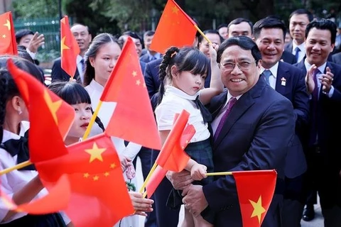 Премьер-министр Фам Минь Тьинь приветствует вьетнамскую общину в Китае (Фото: ВИA)