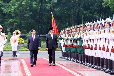 Премьер-министр Фам Минь Тьинь и премьер-министр Малайзии Анвар Ибрагим принимают ряды почетного караула Вьетнамской народной армии. (Фото: ВИА)