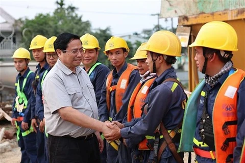 Премьер-министр Фам Минь Тьинь встречается с рабочими на строительной площадке моста через реку Хыонг. (Фото: ВИА)