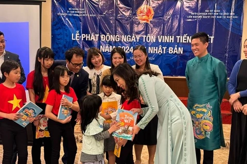 Заместитель министра иностранных дел Вьетнама Ле Тхи Тху Ханг дарит учебники вьетнамского языка ученикам на мероприятии. (Фото: ВИA)