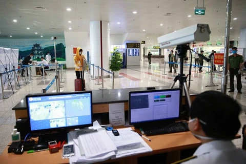 Сотрудник международного аэропорта Нойбай в Ханое проверяет температуру тела пассажиров с помощью теплового сканера (Фото: ВИА)