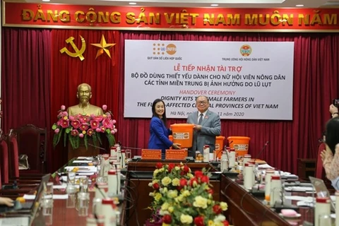 Наоми Китахара, представитель Фонда ООН в области народонаселения (ЮНФПА) во Вьетнаме (слева) передает наборы Тхао Суан Суну, председателю Центрального комитета Союза фермеров Вьетнама. (Фото любезно предоставлено ЮНФПА)