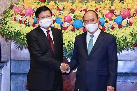 Президент Нгуен Суан Фук (справа) приветствует генерального секретаря Лаосской партии и президента Тонглуна Сисулита во время его визита во Вьетнам в конце июня (Фото: ВИА)