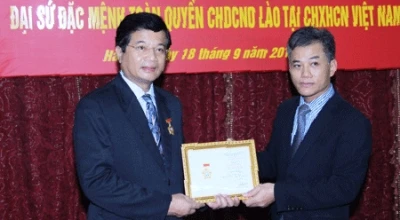 向老挝大使（左）授予“为各民族和平友谊纪念章”。（图片来源：越南共产党电子报） 
