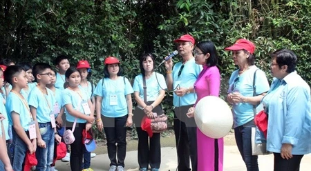 旅居泰国越南老师与学生代表团倾听讲解员诉说有关胡伯伯的故事。（图片来源：越通社）