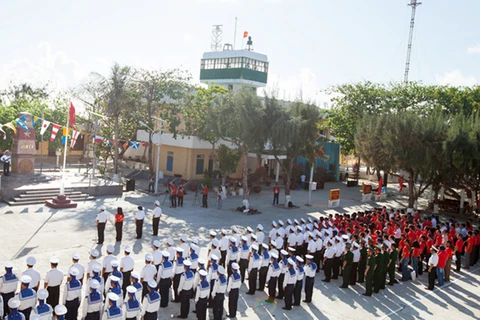 越南侨胞与驻长沙群岛士兵共同向国旗敬礼（图片来源：kinhtedothi.vn）