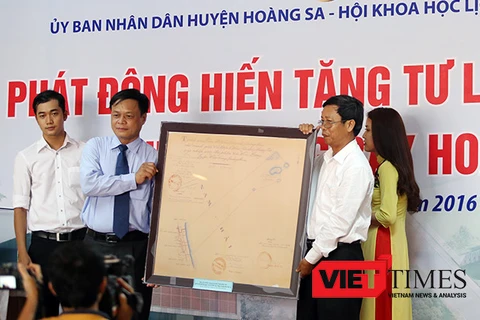 黄沙县人民委员会代表接收由人民捐赠的证明越南对黄沙群岛拥有主权的古地图。