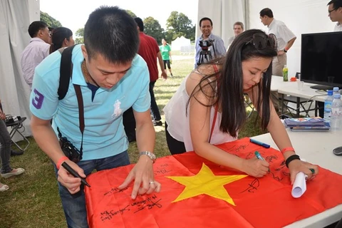 大学生共同在国旗上签字（图片来源：越通社）
