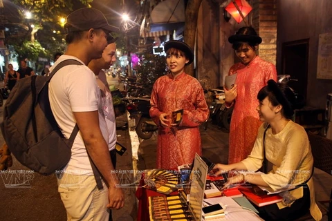 外国游客在河内行帆街28号关帝庙登记观看歌筹表演