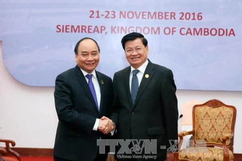 越南政府总理阮春福（左）与老挝政府总理通伦•西苏里（右）在第九届柬老越发展三角区峰会期间进行会晤。（图片来源：越通社）