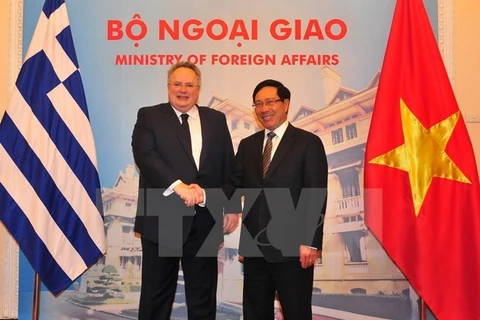 越南政府副总理兼外交部长范平明与希腊外交长尼科斯亲切握手（图片来源：越通社