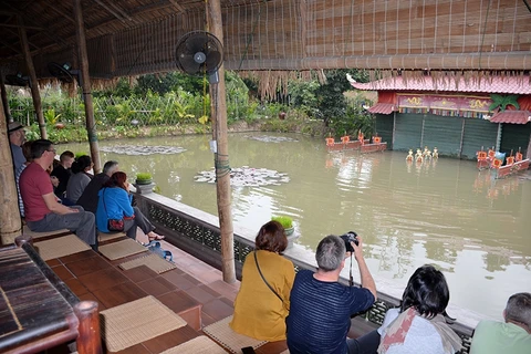 外国游客在安德乡看水上木偶戏表演（图片来源：越南人民报）