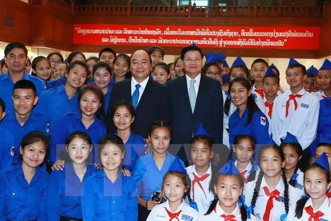 附图：越南政府总理阮春福与老挝总理通伦与两国青年代表合影。（图片来源：越通社）