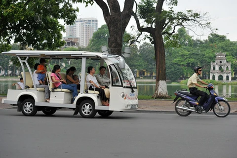 游客们乘坐电瓶车游览河内街道。
