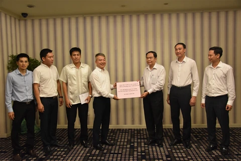 越南驻老挝大使馆公使衔参赞阮青松将捐款交给越共中央委员、祖国阵线中央委员会主席陈青敏。
