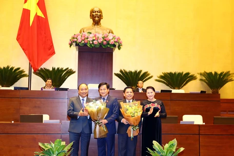 政府总理阮春福（左一）和国会主席阮氏金银（右一）向阮文体和黎明慨赠送鲜花。（图片来源：越通社）