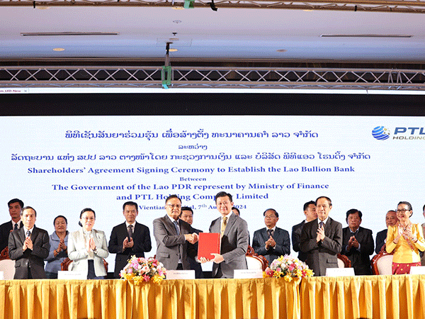 Finance Minister Santiphab Phomvihane (left) exchanges the signed shareholders agreement documents with Chairman of PTL Holding Co., Ltd. Dr Chanthone Sitthixay. (Photo: www.vientianetimes.org.la) 