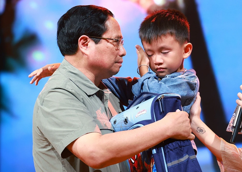 PM Pham Minh Chinh gives encouragement to a boy named Nguyen Quoc Bao, whose father and elder sister were washed away by a flood while the three were crossing a bridge in Cau Treo hamlet of Yen Thuan commune, Ham Yen district, Tuyen Quang province. (Photo: VNA)