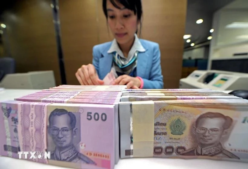 A bank teller counts baht notes in Bangkok, Thailand. (Photo: AFP/VNA)