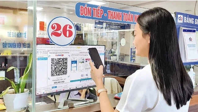 A woman pays for medical examination via QR code at a hospital in Hanoi. (Photo: nhandan.vn)