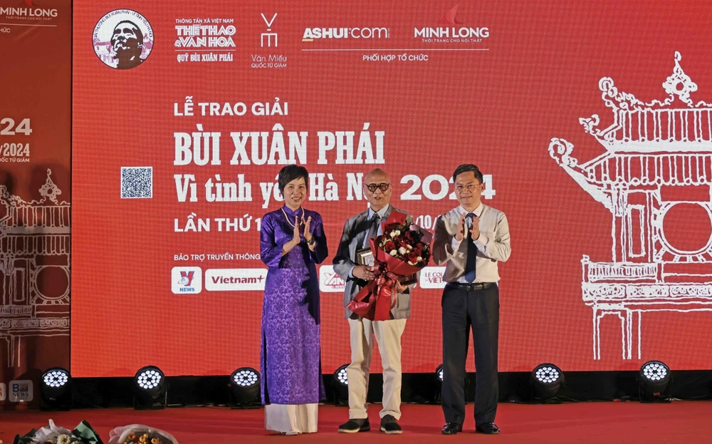 VNA General Director Vu Viet Trang (left) and Vice Chairman of the Hanoi People’s Committee Ha Minh Hai (right) presents the Grand Prize of the “Bui Xuan Phai: For the Love of Hanoi” Awards to architect Hoang Dao Kinh at the ceremony on October 8. (Photo: VNA)