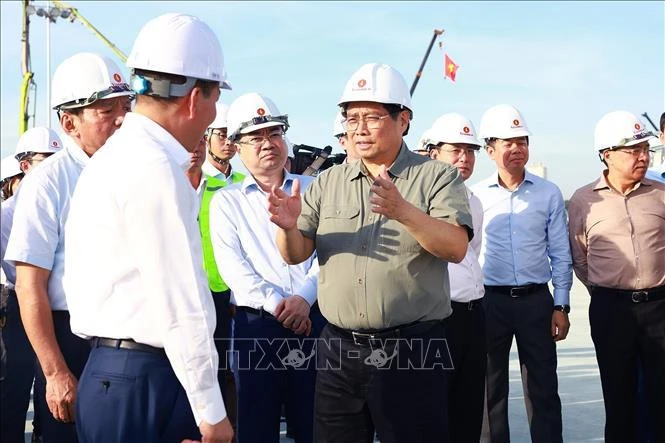 PM Pham Minh Chinh talks to officials while examining the national exhibition and fair centre project in Dong Anh district of Hanoi on October 25. (Photo: VNA)