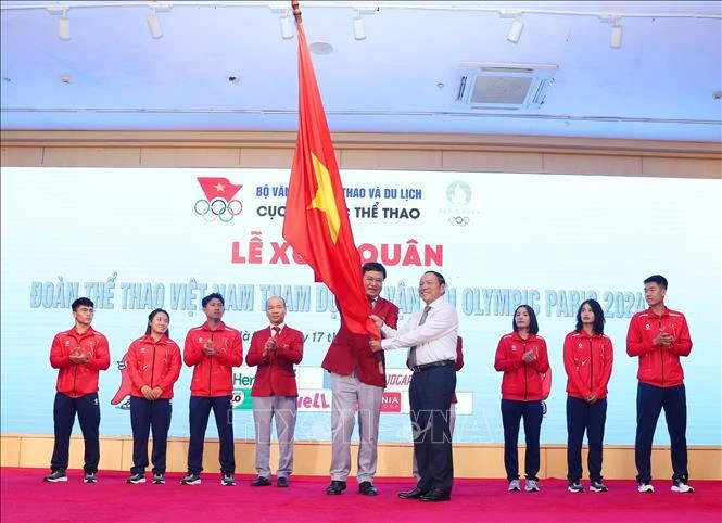 Le ministre de la Culture, des Sports et du Tourisme, Nguyen Van Hung (droite), remet le drapeau symbolisant la détermination à concourir au chef de la délégation vietnamienne aux JO de Paris 2024, Dang Ha Viet. Photo: VNA