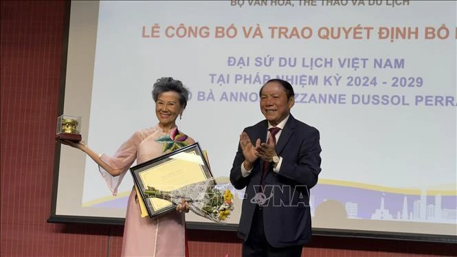 Le ministre vietnamien de la Culture, des Sports et du Tourisme, Nguyen Van Hung, remet la décision de reconduction de Anoa Suzanne Dussol Perran comme ambassadrice du tourisme du Vietnam en France. Photo: VNA