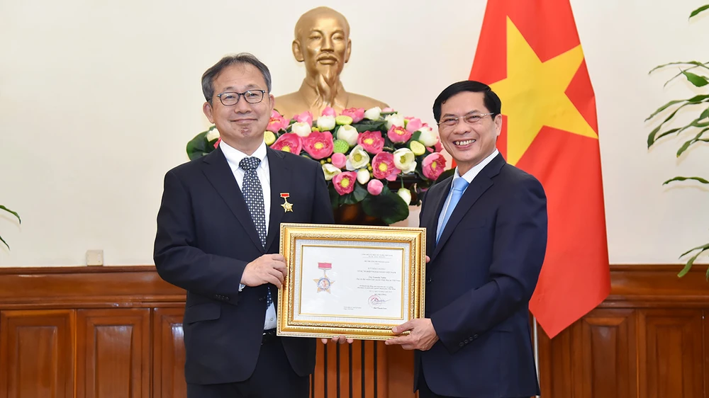 裴青山向山田贵雄大使授予“致力于越南外交事业”纪念章。图自越通社