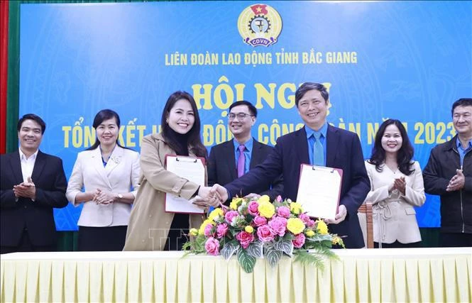 Le dirigeant de la Confédération du travail de la province de Bac Giang signe un accord de coopération sur le programme de bien-être des travailleurs avec la société par actions du commerce international HOGI Group. Photo: VNA
