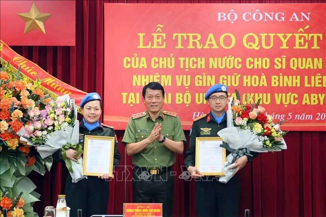 Le vice-ministre de la Sécurité publique Luong Tam Quang présente la décision du président à deux agents de la Sécurité publique d'effectuer des missions de maintien de la paix des Nations Unies. Photo: VNA