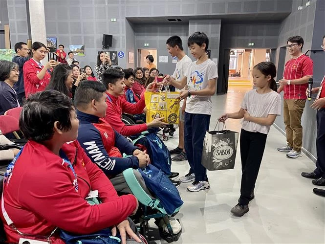 Des Vietnamiens en France offrent des cadeaux aux sportifs handicapés vietnamiens. Photo: VNA